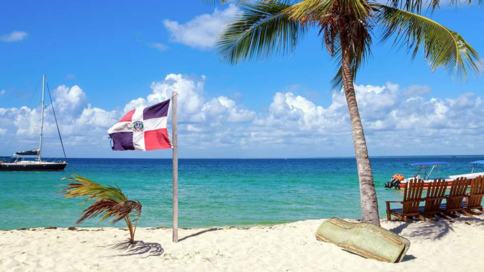 Tropical beach paradise in Punta Cana, Dominican Republic. White sand, clear turquoise water, palm tree, and the Dominican flag waving gently. Caribbean vacation destination.