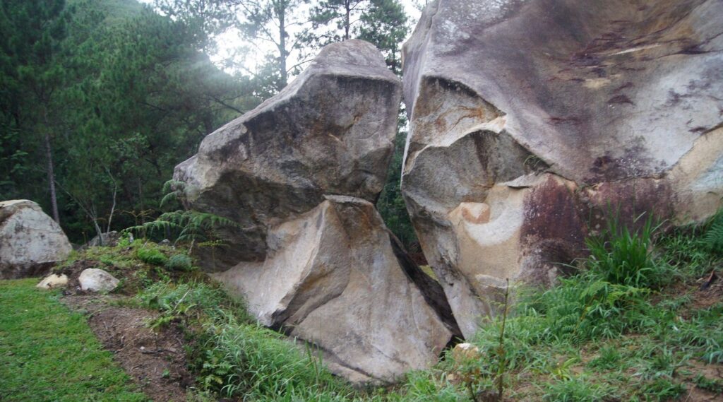 Natural rock formations in a grassy, wooded area. La Piedra Letrada rock formation, Dominican Republic.