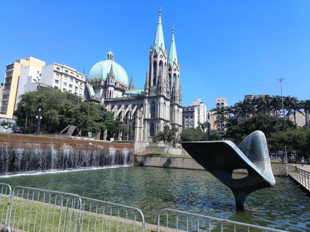 The São Paulo Metropolitan Cathedral and surrounding plaza with a water feature under a clear blue sky