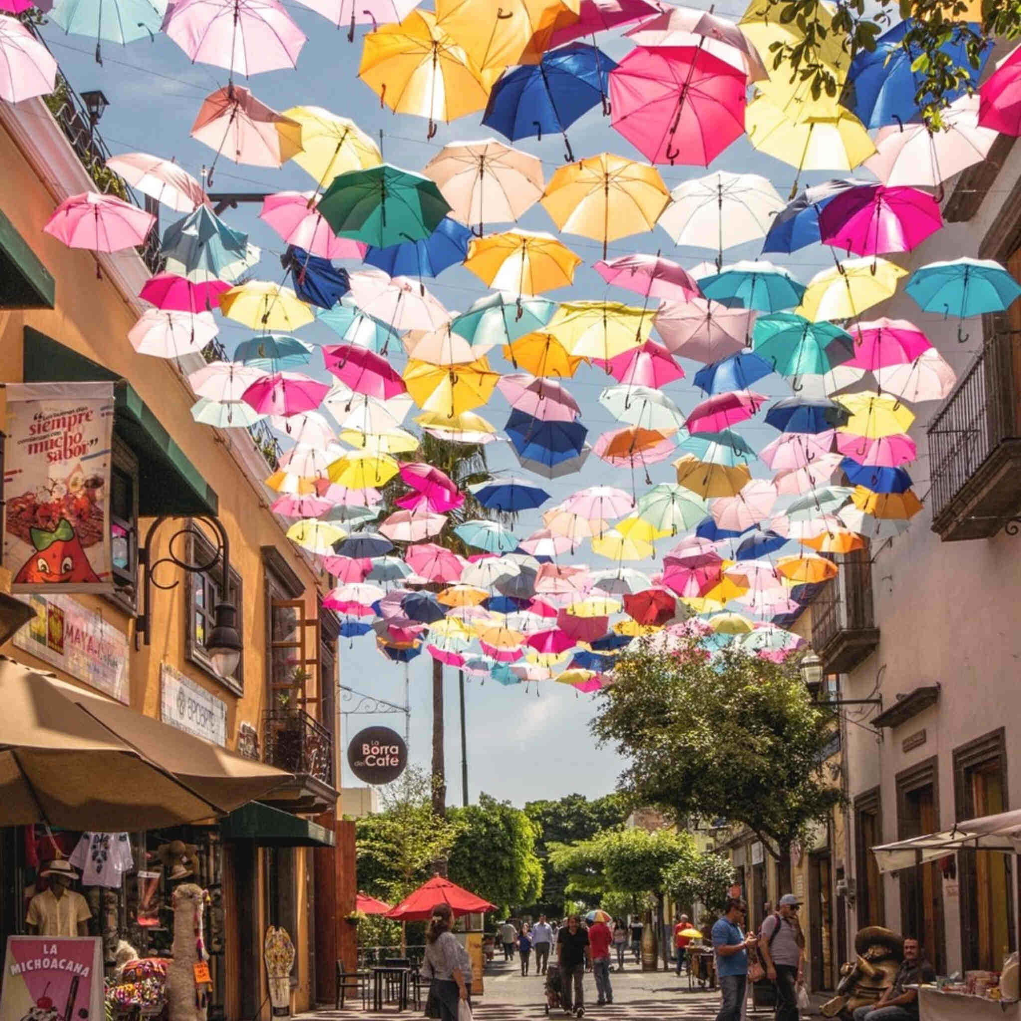 Umbrella sky art installation above a bustling walkway in Tlaquepaque, Guadalajara